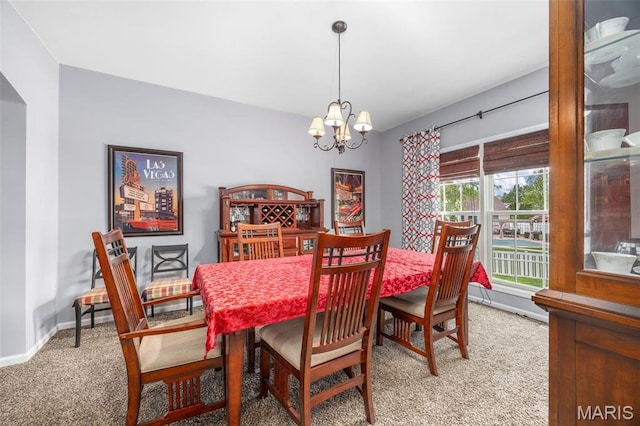 carpeted dining room featuring a chandelier and baseboards