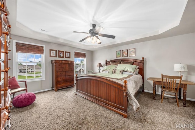 carpeted bedroom with a tray ceiling and baseboards