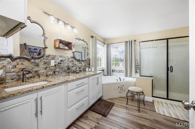 full bathroom featuring tasteful backsplash, wood finished floors, a garden tub, double vanity, and a stall shower