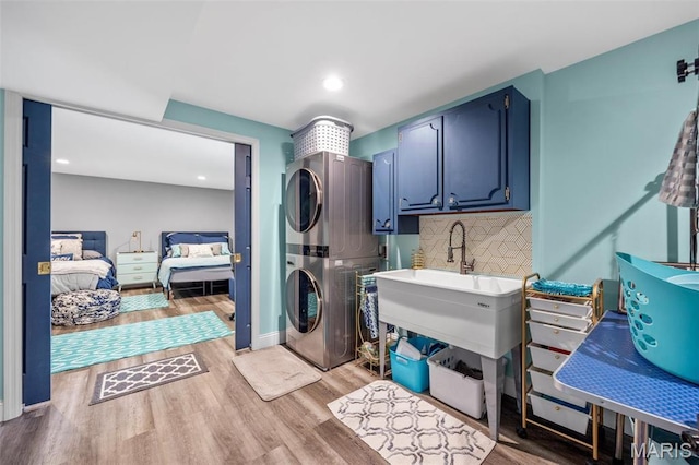 laundry area featuring estacked washer and dryer, light wood finished floors, cabinet space, and recessed lighting