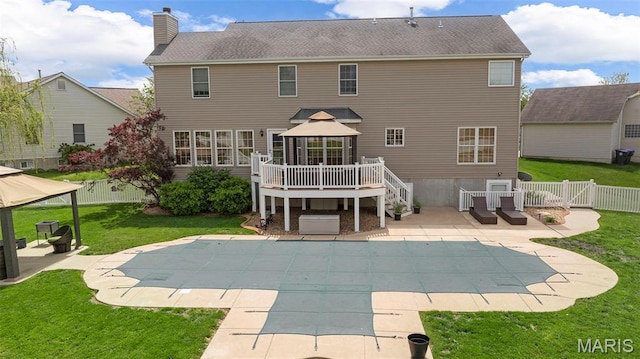 rear view of house with a gazebo, a patio area, a chimney, a deck, and a covered pool
