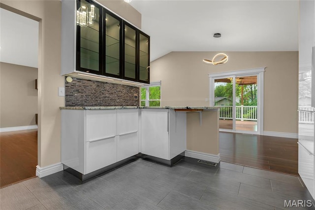 2022 Tramore Ct, Chesterfield, MO 63017 - kitchen featuring lofted ceiling, stone counters, glass insert cabinets, tasteful backsplash, and baseboards