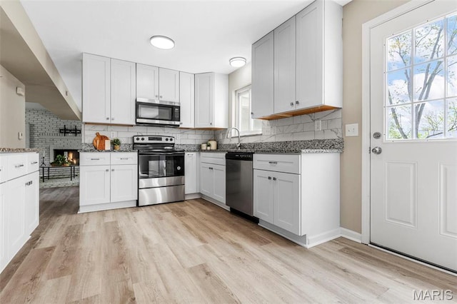 948 Barbara Ann Ln, Ellisville, MO 63021 - kitchen featuring appliances with stainless steel finishes, light wood-type flooring, decorative backsplash, stone countertops, and white cabinetry