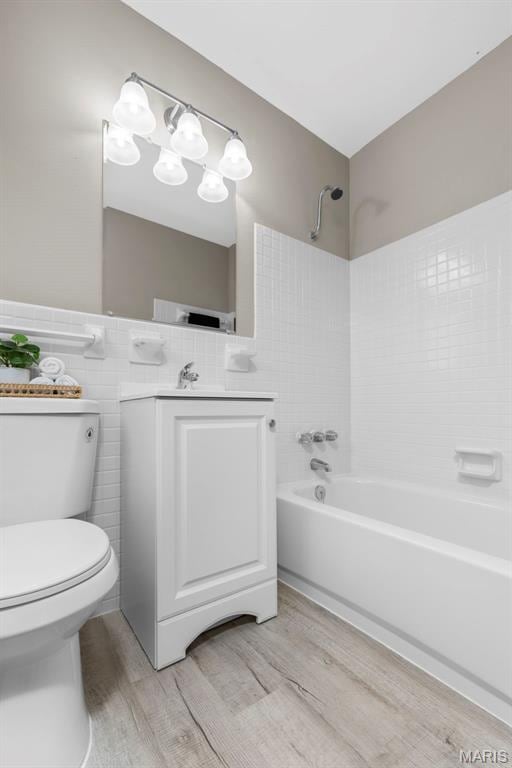 948 Barbara Ann Ln, Ellisville, MO 63021 - bathroom featuring shower / bath combination, wood finished floors, vanity, and tile walls