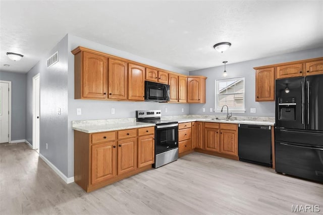 705 Fulton St, Gillespie, IL 62033 - kitchen with black appliances, light countertops, light wood-style flooring, a sink, and baseboards