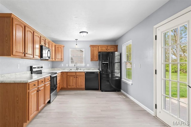 705 Fulton St, Gillespie, IL 62033 - kitchen featuring black appliances, light countertops, light wood-style flooring, baseboards, and decorative light fixtures