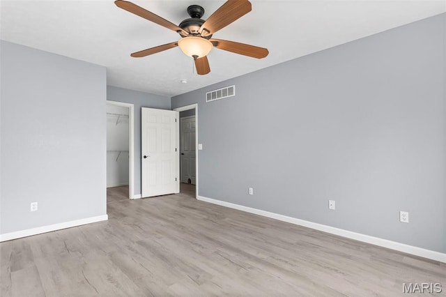 705 Fulton St, Gillespie, IL 62033 - unfurnished bedroom with baseboards, wood finished floors, a ceiling fan, a walk in closet, and a closet