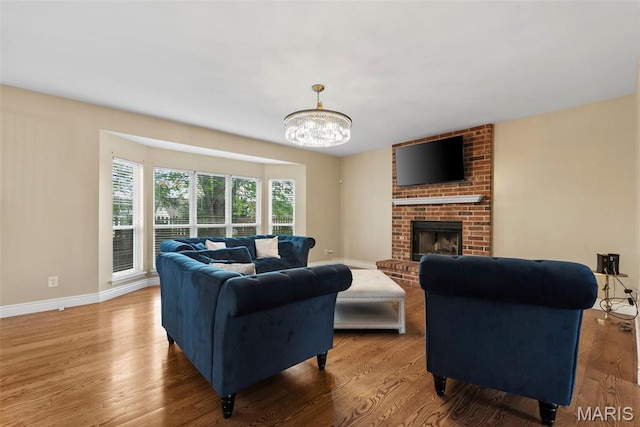 living area with a chandelier, wood finished floors, a fireplace, and baseboards
