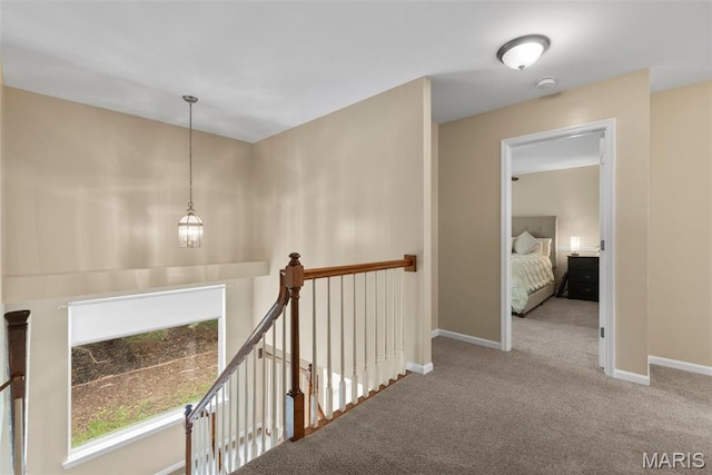 hall with an upstairs landing, carpet, and baseboards
