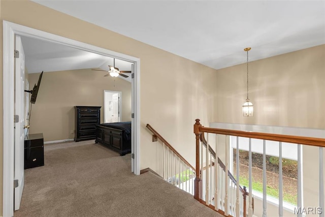 hall with an upstairs landing, carpet, lofted ceiling, and baseboards