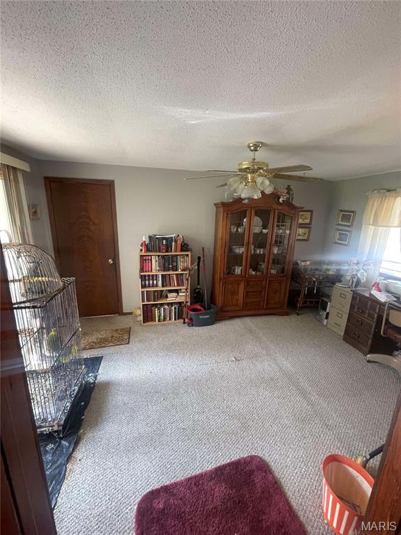 living room featuring carpet flooring, a ceiling fan, and a textured ceiling