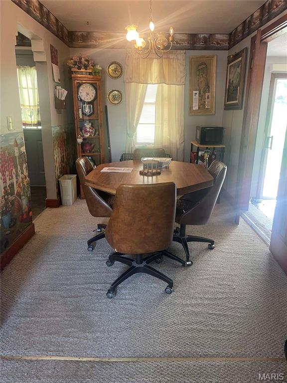 carpeted dining space with healthy amount of natural light, a chandelier, and an office area
