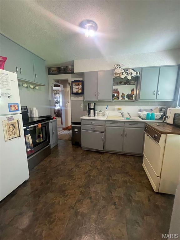 kitchen featuring stainless steel electric range, freestanding refrigerator, open shelves, a textured ceiling, and gray cabinets