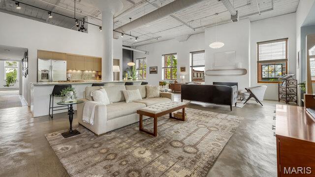 4100 Laclede Ave Unit 314, Saint Louis, MO 63108 - living room featuring rail lighting, finished concrete floors, a high ceiling, healthy amount of natural light, and a fireplace