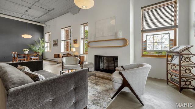 4100 Laclede Ave Unit 314, Saint Louis, MO 63108 - living room featuring a glass covered fireplace, rail lighting, healthy amount of natural light, a towering ceiling, and baseboard heating