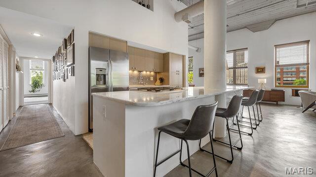 4100 Laclede Ave Unit 314, Saint Louis, MO 63108 - kitchen with finished concrete floors, decorative columns, stainless steel appliances, light countertops, and a breakfast bar