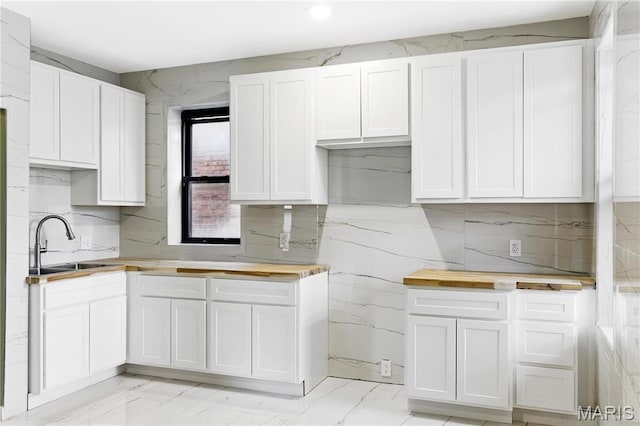 4402 Arco Ave, Saint Louis, MO 63110 - kitchen featuring a sink, light marble finish floors, white cabinets, and backsplash