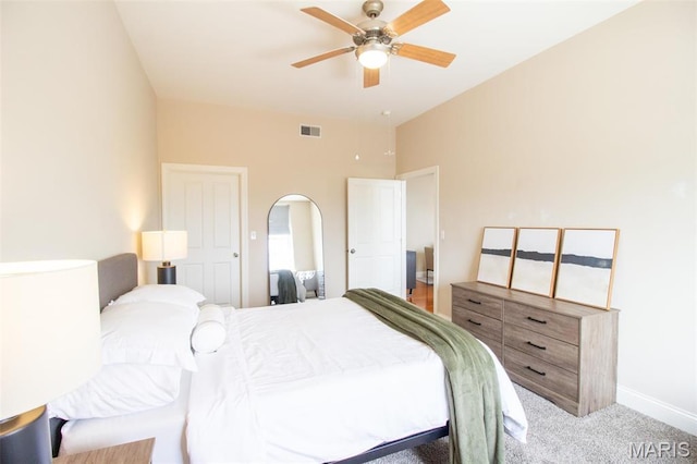 carpeted bedroom featuring arched walkways, ceiling fan, and baseboards