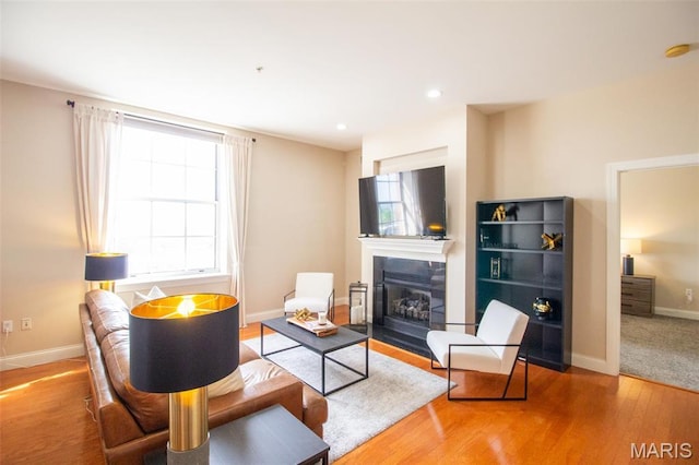 living room with a fireplace with flush hearth, healthy amount of natural light, wood finished floors, baseboards, and recessed lighting