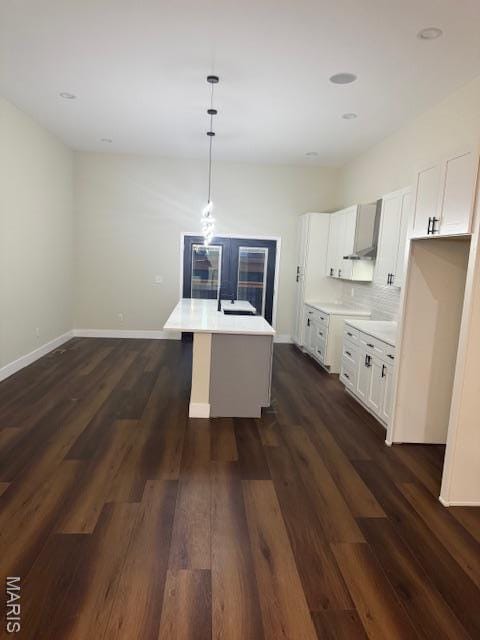 4209 Norfolk Ave, Saint Louis, MO 63110 - kitchen featuring dark wood-type flooring, a center island with sink, light countertops, hanging light fixtures, and white cabinets