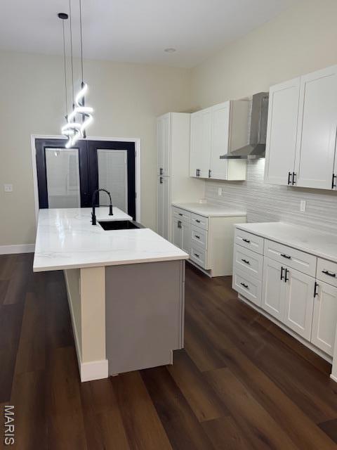 4209 Norfolk Ave, Saint Louis, MO 63110 - kitchen featuring wall chimney range hood, a sink, a center island with sink, dark wood-type flooring, and white cabinetry