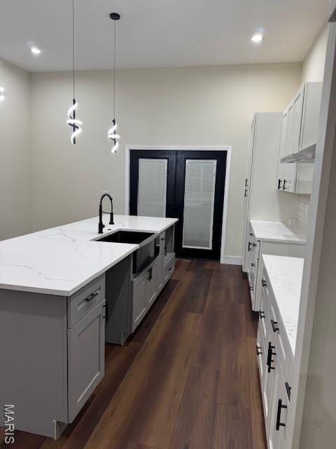 4209 Norfolk Ave, Saint Louis, MO 63110 - kitchen with a sink, light stone counters, dark wood-type flooring, a kitchen island with sink, and recessed lighting