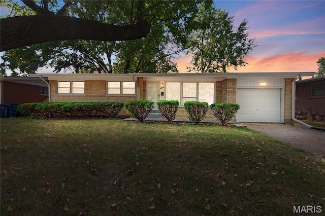 view of front of property with an attached garage, brick siding, a lawn, and concrete driveway