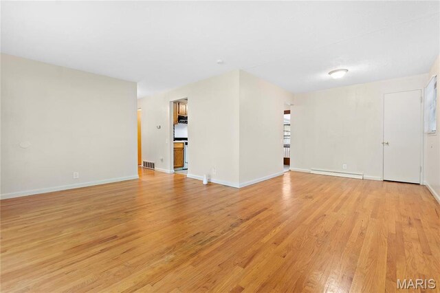 unfurnished living room with a baseboard heating unit, light wood-style floors, and baseboards