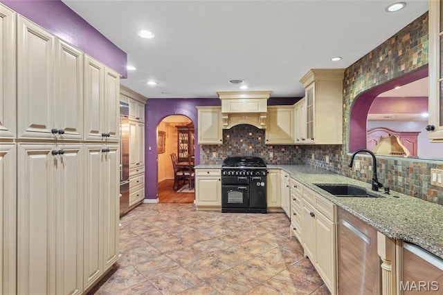2048 Pontoon Rd, Granite City, IL 62040 - kitchen with range with two ovens, cream cabinets, a sink, arched walkways, and light stone counters