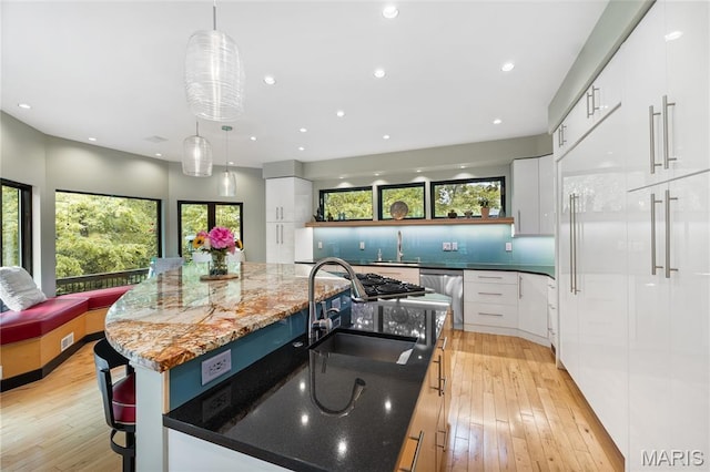 400 Gabriel Dr, Kirkwood, MO 63122 - kitchen featuring modern cabinets, appliances with stainless steel finishes, light wood-type flooring, an island with sink, and white cabinetry