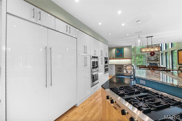 400 Gabriel Dr, Kirkwood, MO 63122 - kitchen with stainless steel appliances, white cabinets, a fireplace, recessed lighting, and light wood-style flooring