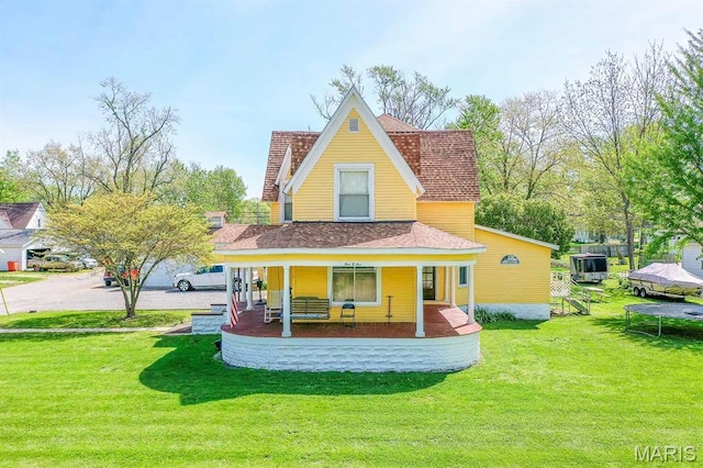 rear view of property with a porch, a yard, and a shingled roof