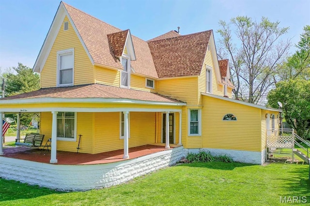 back of property featuring a lawn, covered porch, and a shingled roof