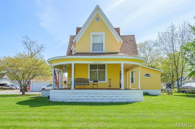 view of front of house with a chimney, covered porch, a front yard, and roof with shingles