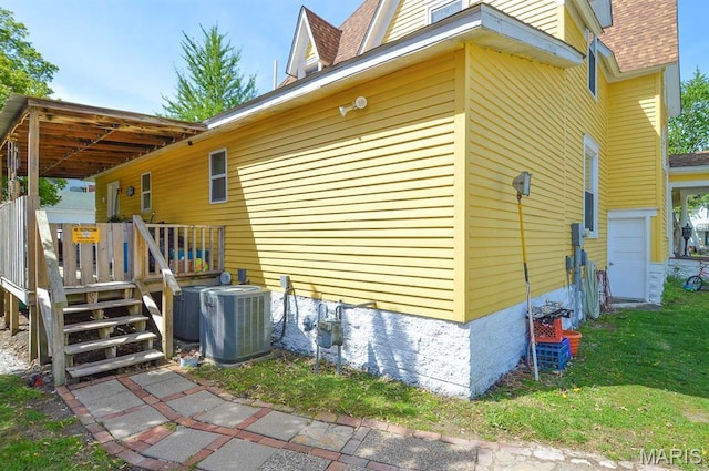 view of side of home featuring central air condition unit, a garage, roof with shingles, and a wooden deck