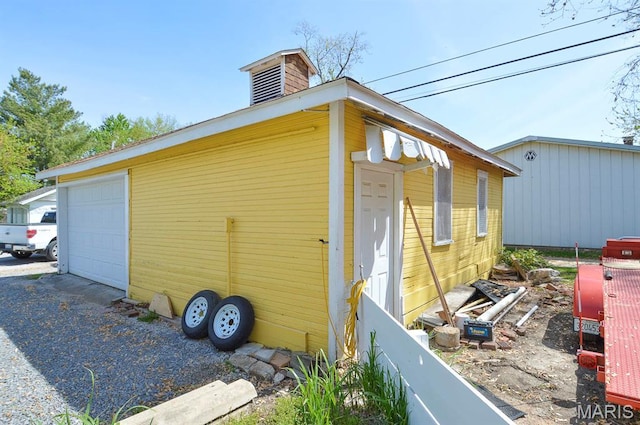view of side of property with a detached garage, a chimney, and an outdoor structure