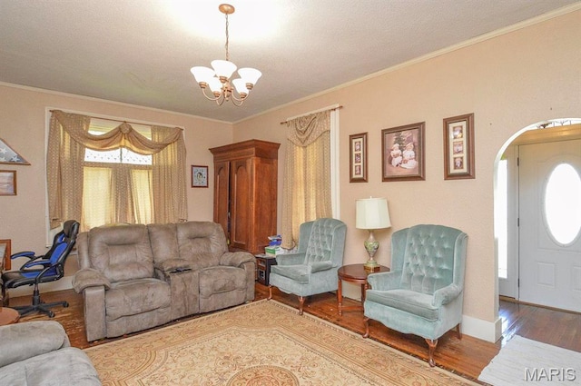 living room featuring wood finished floors, a chandelier, baseboards, ornamental molding, and arched walkways