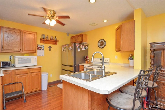 kitchen with white appliances, a ceiling fan, light countertops, a peninsula, and recessed lighting