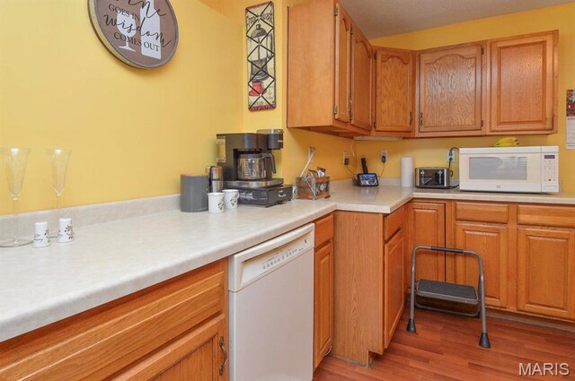 kitchen with white appliances, light countertops, light wood-style floors, and brown cabinets