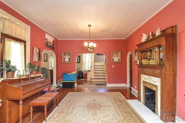 foyer with arched walkways, ornamental molding, a high end fireplace, wood finished floors, and stairs