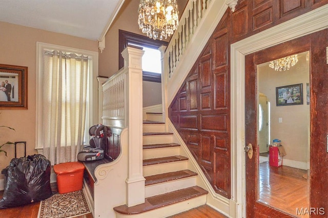 staircase featuring a chandelier, ornate columns, wood finished floors, and baseboards