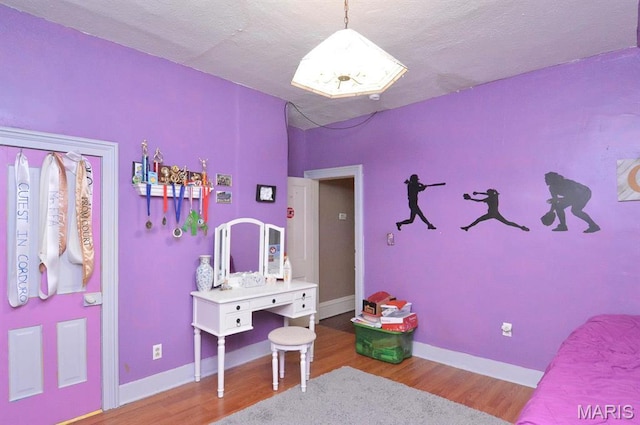 bedroom featuring wood finished floors, a textured ceiling, and baseboards