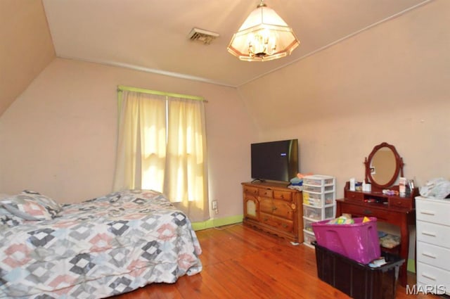 bedroom featuring vaulted ceiling, wood finished floors, a chandelier, and baseboards