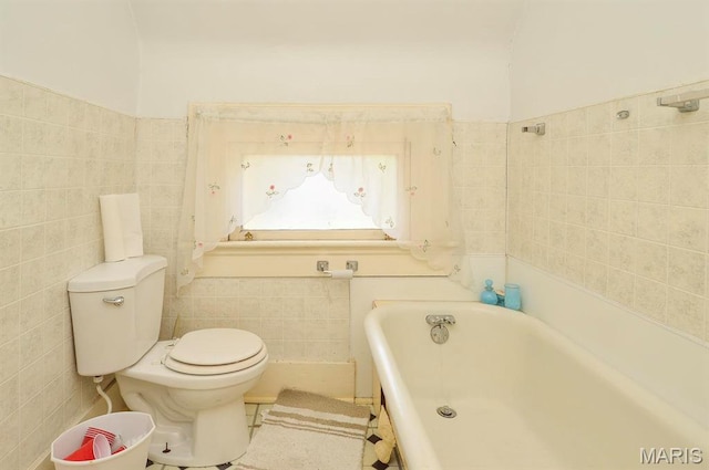 full bathroom with tile walls, a tub to relax in, and toilet
