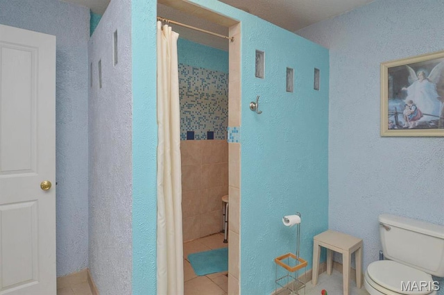 full bathroom featuring toilet, tile patterned flooring, curtained shower, and a textured wall