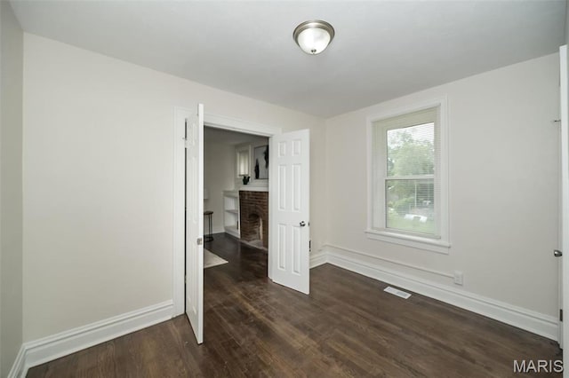 4117 Ravenwood Ave, Saint Louis, MO 63121 - unfurnished bedroom featuring a fireplace, dark wood-style floors, and baseboards