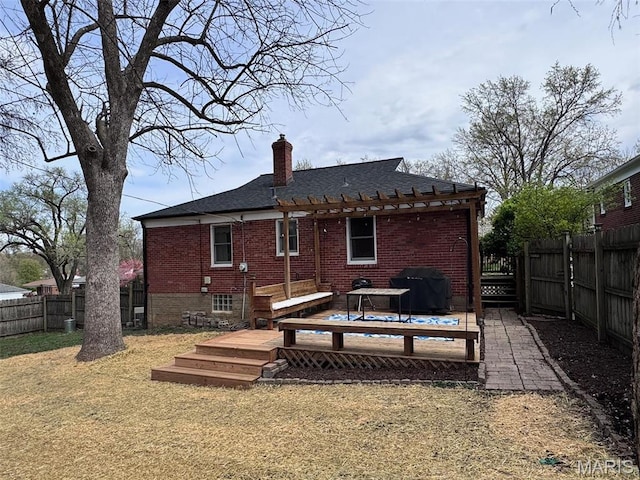 rear view of property with brick siding, a pergola, a chimney, a wooden deck, and roof with shingles