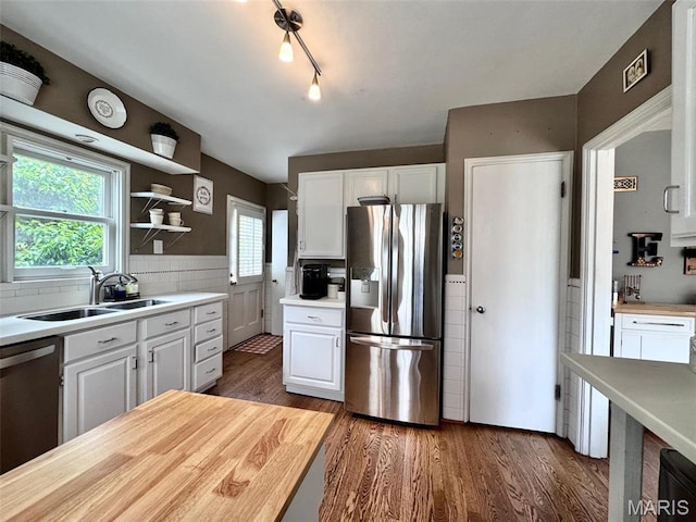 kitchen with stainless steel fridge, a sink, white cabinetry, dishwasher, and wood finished floors