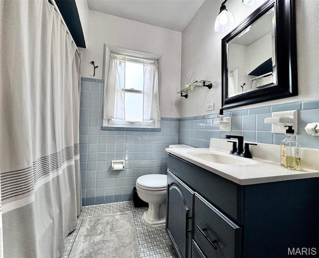 bathroom featuring tile walls, tile patterned flooring, toilet, vanity, and wainscoting