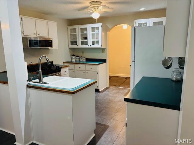 305 Frisco St, Steelville, MO 65565 - kitchen with stainless steel microwave, white cabinetry, ceiling fan, a sink, and glass insert cabinets